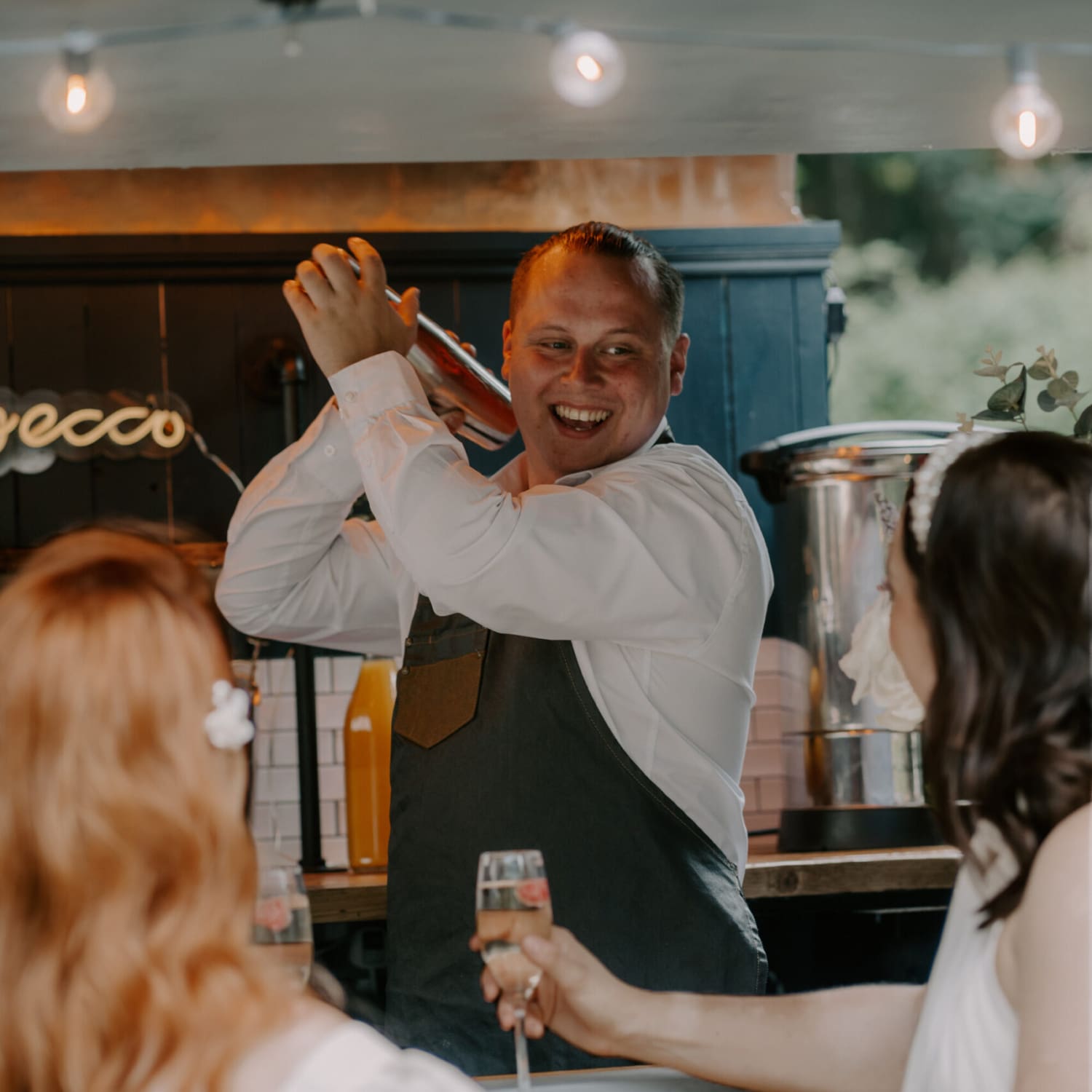 The Bubble Box staff shaking a cocktail at a wedding in the mobile horsebox bar.